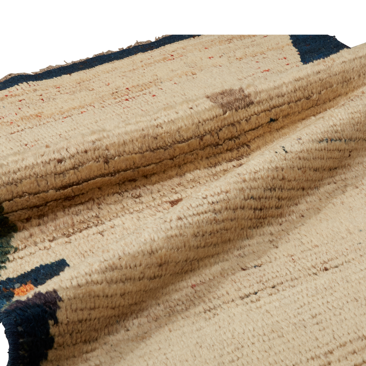 A close-up of a textured woven rug in natural beige with dark navy blue geometric accents and subtle brown and orange flecks.