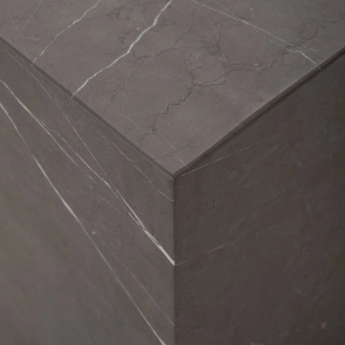 Duvall Side Table close-up of a top corner in warm gray Petra Grey marble, highlighting the crisp mitred edges and fine white veining.
