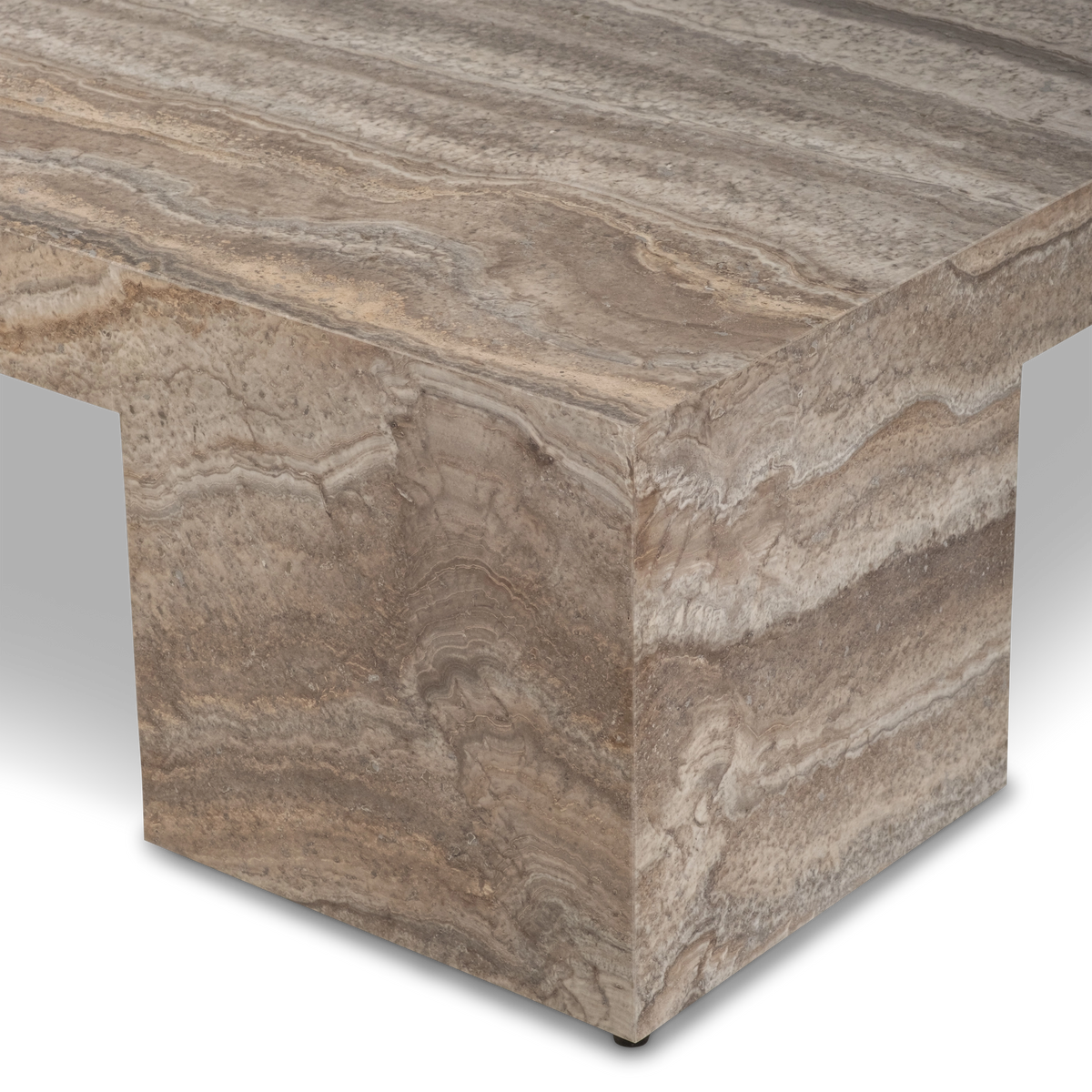 Close-up of the Duvall Coffee Table's corner and leg in Taupe travertine, highlighting the honed top, layered veining, and a small dark foot at the base.