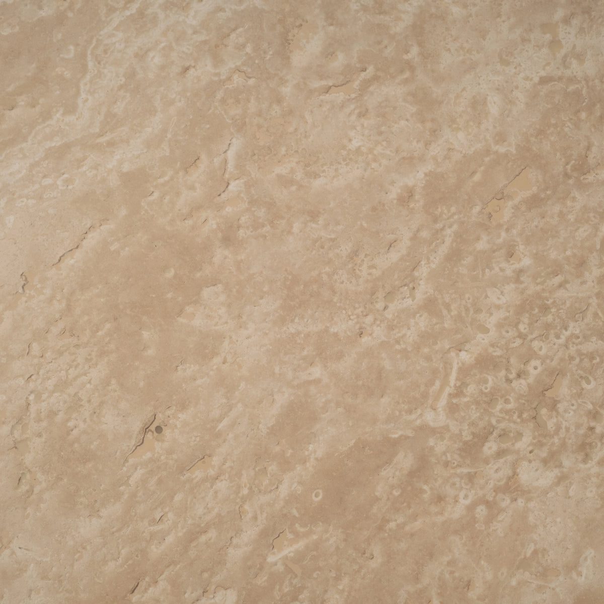 Close-up of the Warm Beige travertine surface of the Meta Round Coffee Table, with cream and ivory veining, fine pitting, and subtle tan variation across the honed face.