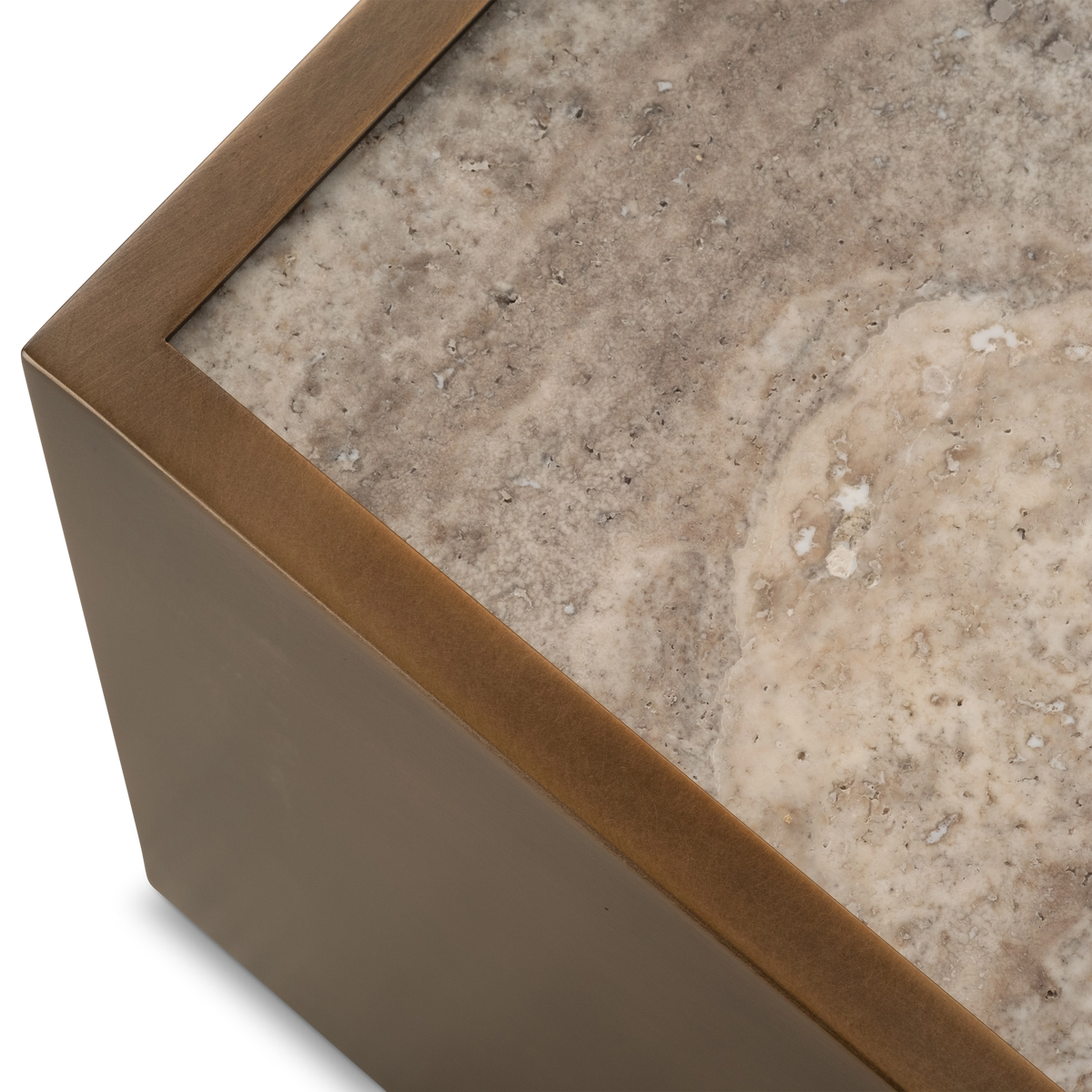 Close-up showing the corner of the Pedra Rectangular Coffee Table in Aged Bronze, with the brushed metal rim framing the pitted taupe travertine top and its cream mottling.