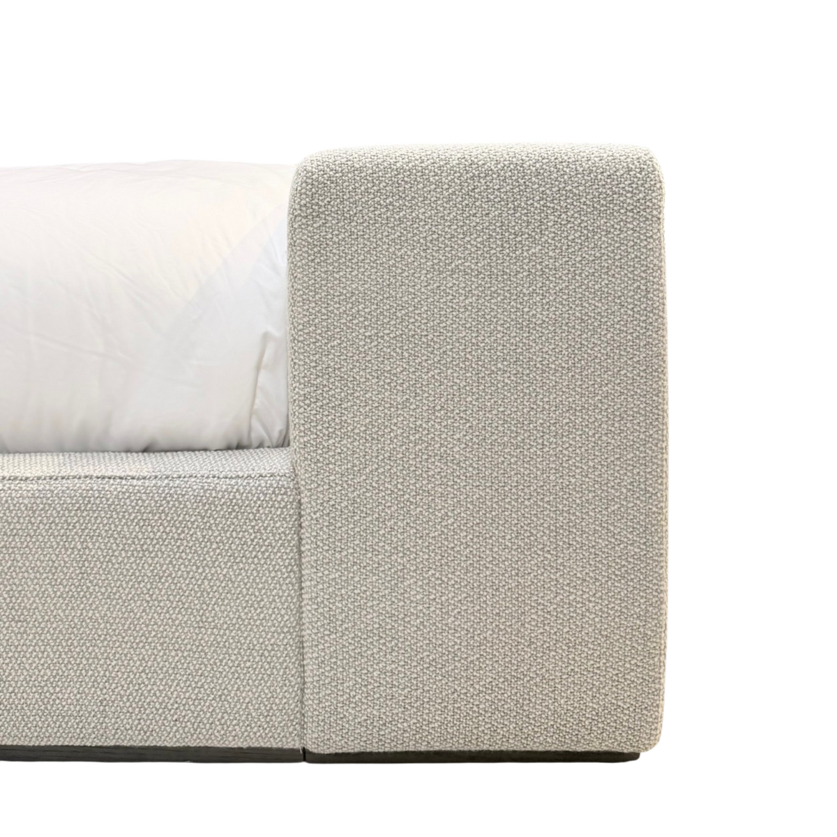 Close-up of the Vital King Bench Footboard Bed showing the softly textured neutral upholstery and rounded edge of the bench-style footboard.