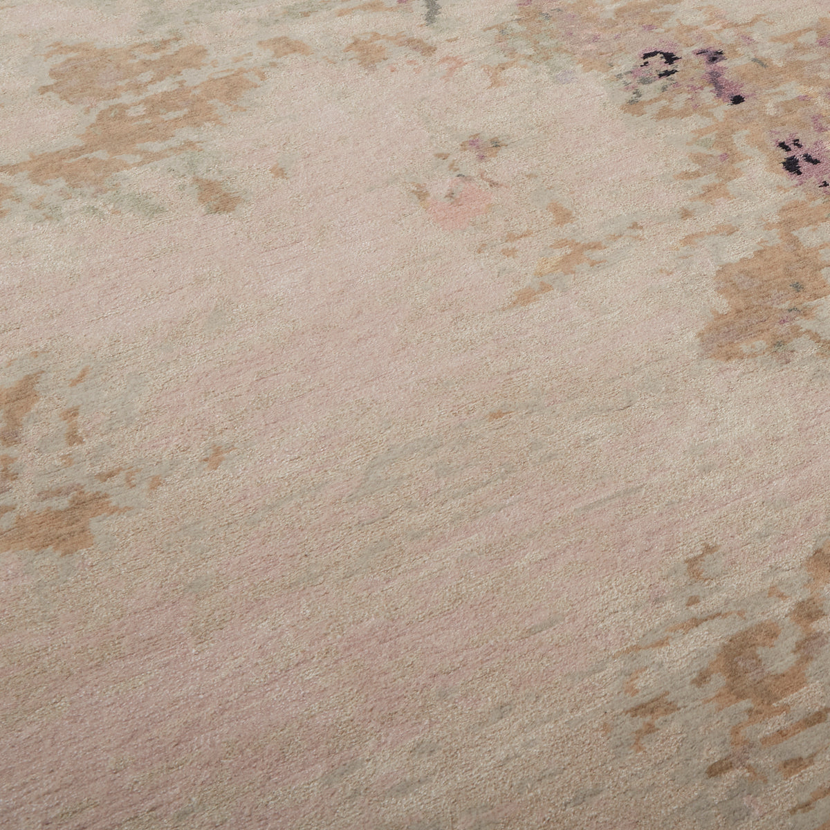 A close-up of a textured area rug with a soft, abstract pattern in dusty pink, beige, and light brown tones.