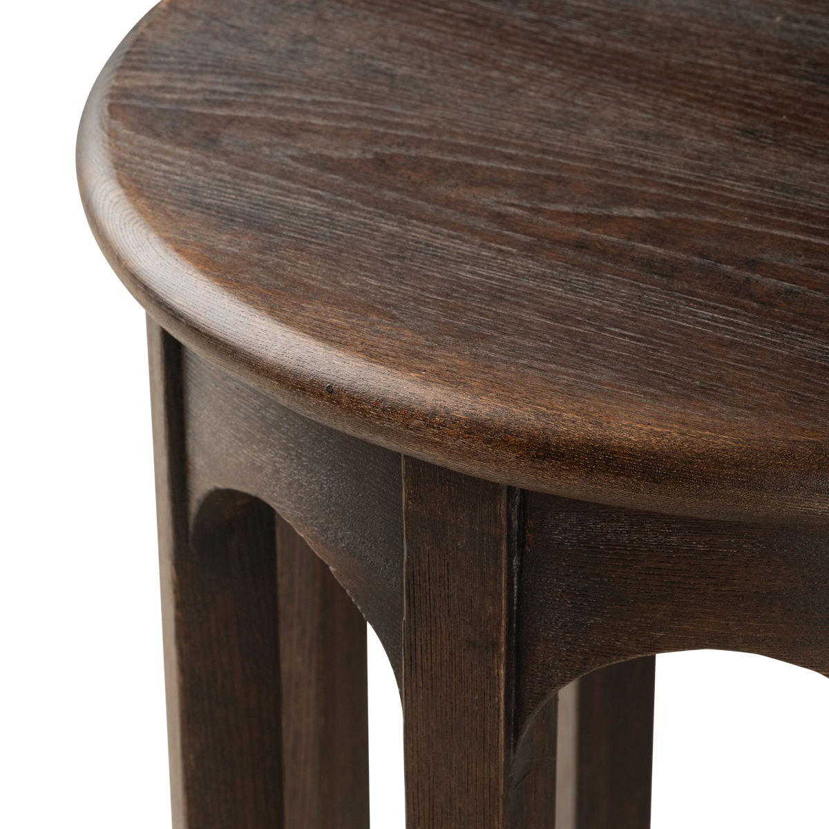 Close-up showing the rounded edge of the Calloway Side Table’s dark brown elm top, with visible grain, a small arched apron, and a square leg below.