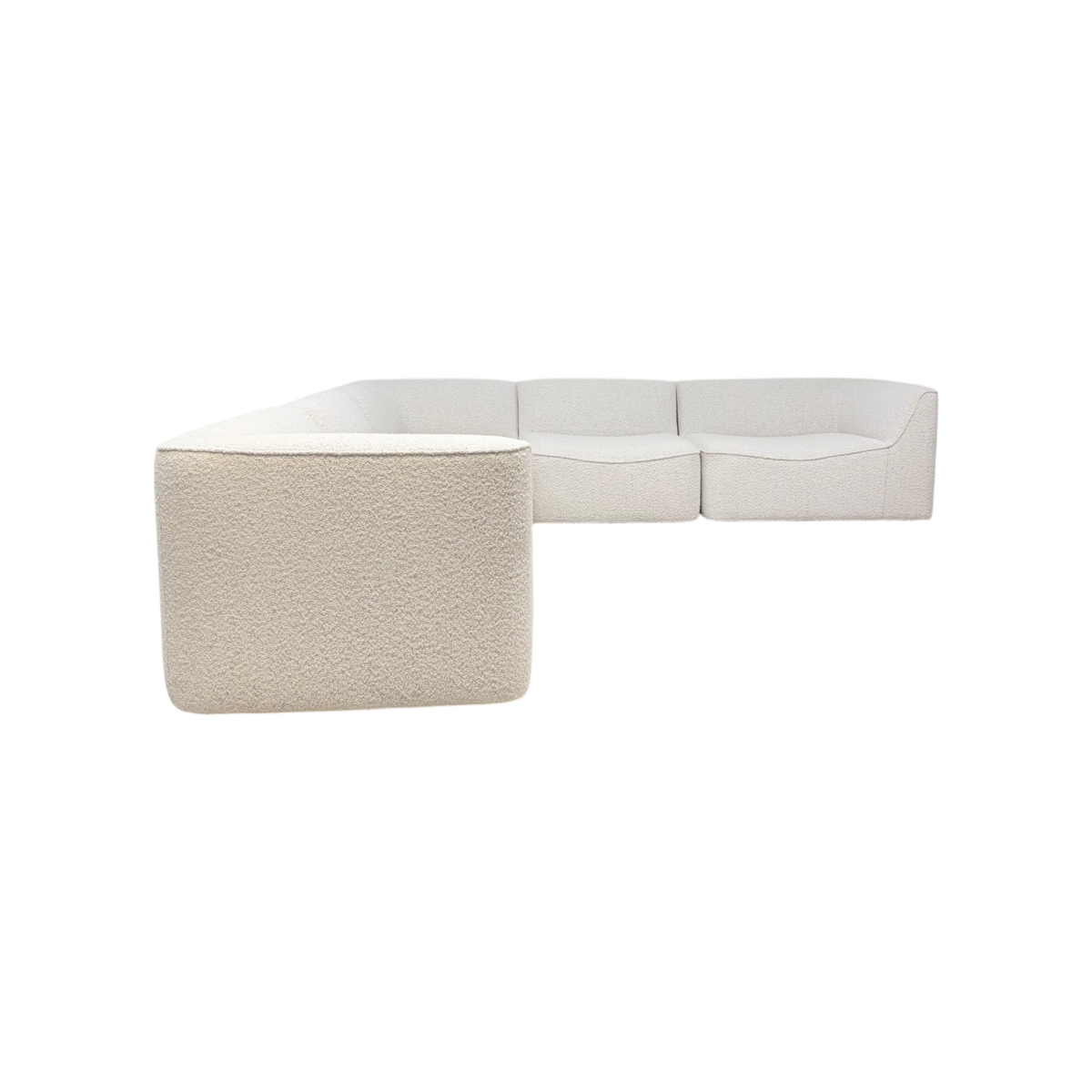 Bento Modular Sectional in ivory bouclé, angled side view highlighting the modular corner arrangement, wraparound back, rounded arms, and plush textured upholstery.