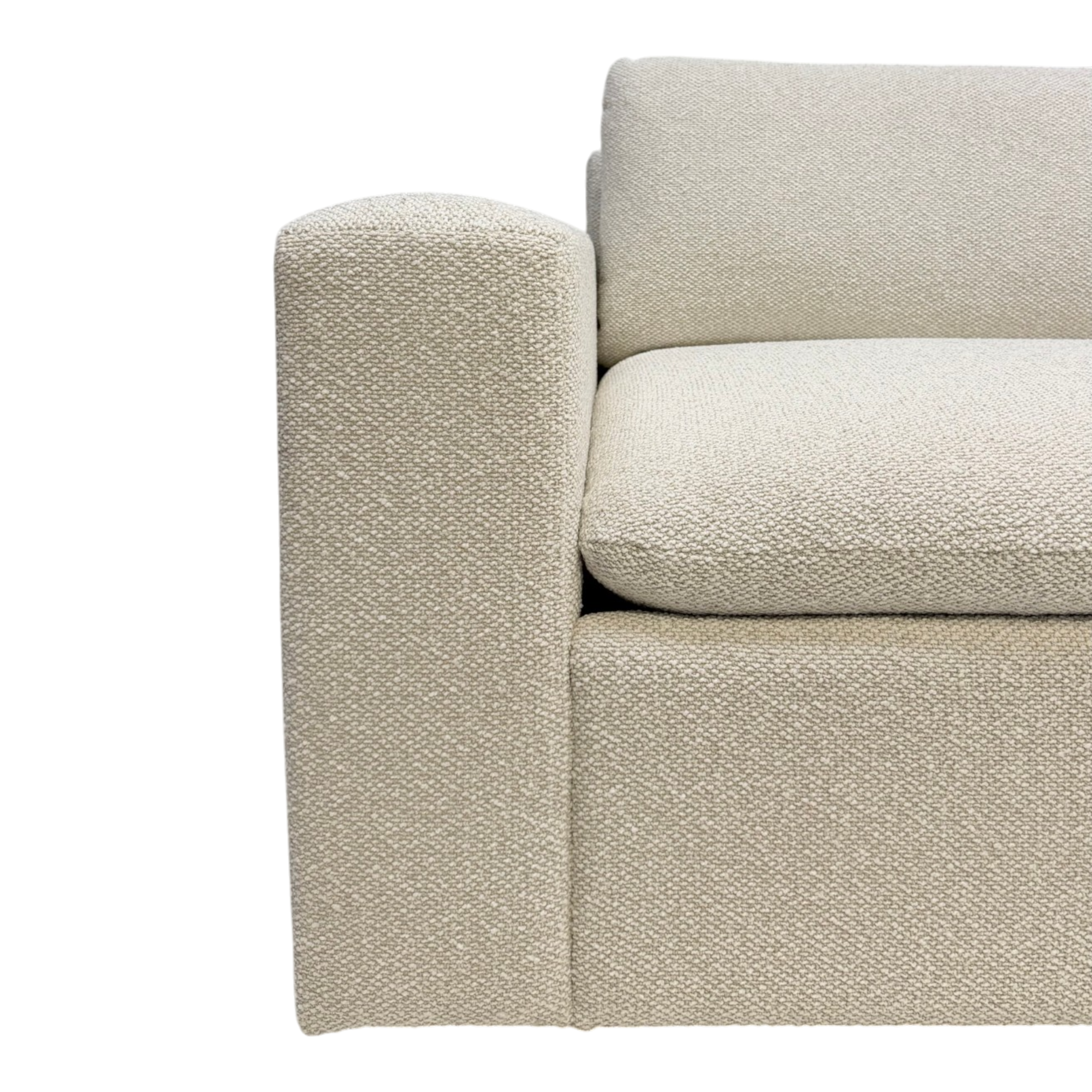 Tempo Modular Sectional close-up showing textured ivory upholstery across the arm, loose seat cushion, and back cushion with a soft woven finish.