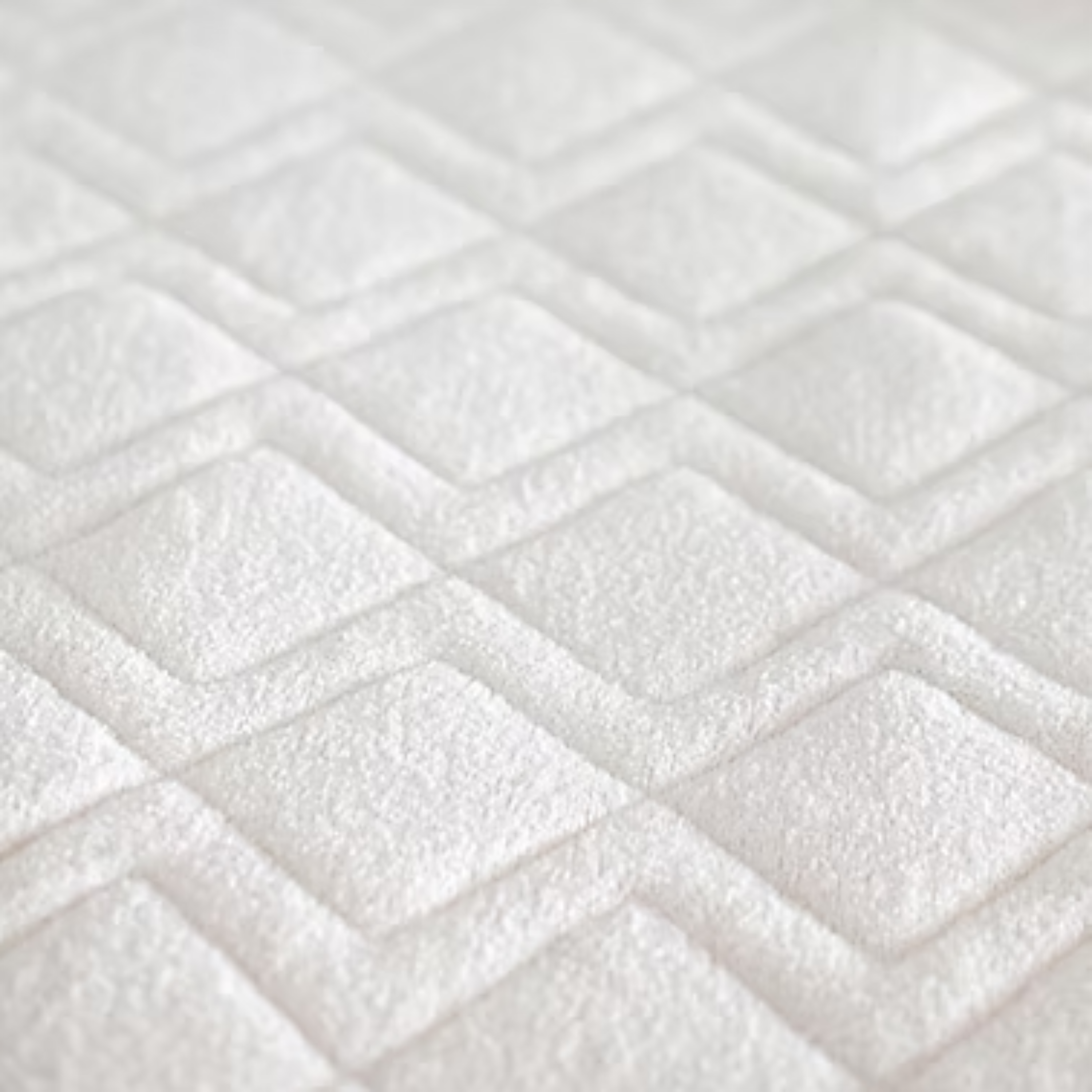 St. Dormier XL Twin mattress protector close-up showing soft white cotton terry fabric with raised geometric quilting and New Zealand wool fill.