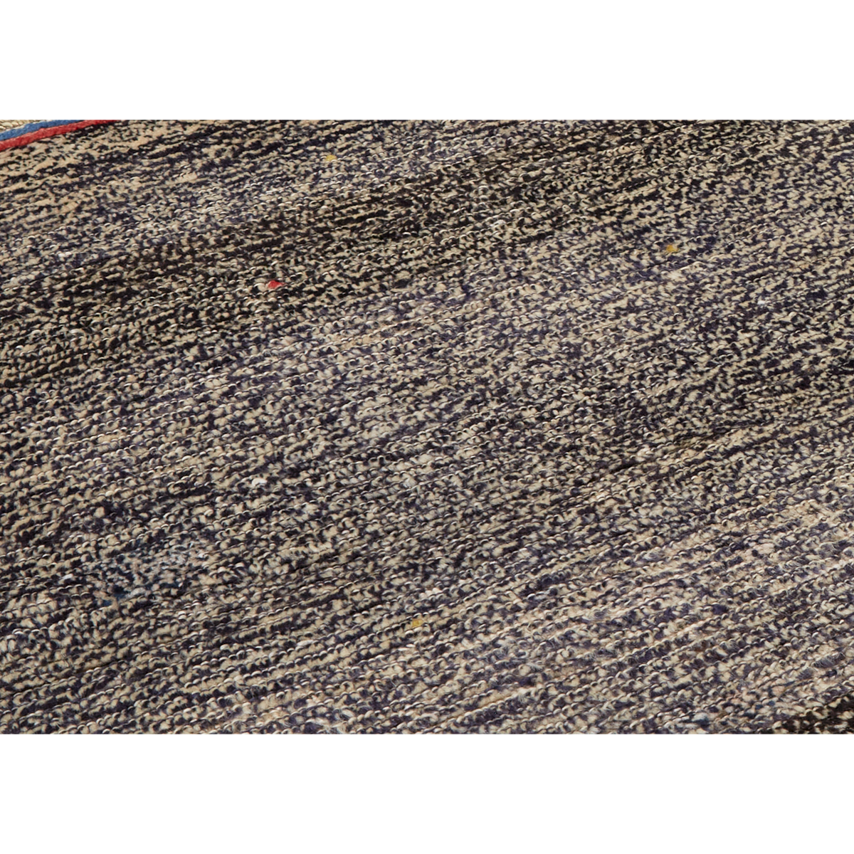 A close-up of a textured rug or carpet with a dense, mottled pattern of black, beige, and brown tones.