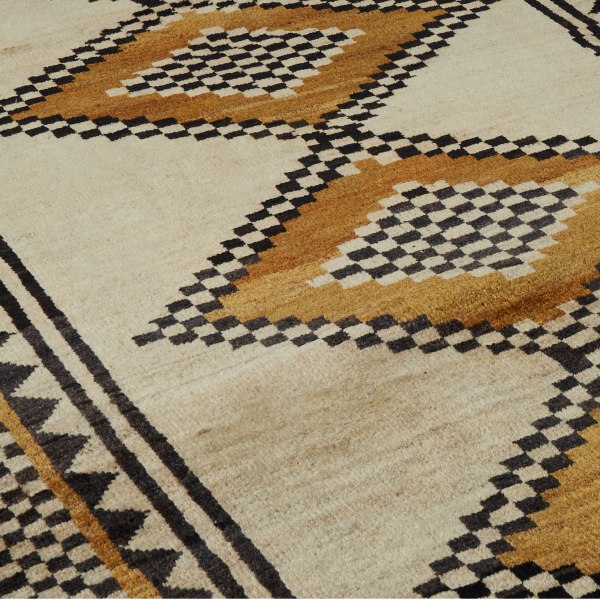 A close-up of a woven rug with a Southwestern geometric pattern in beige, black, and ochre brown.