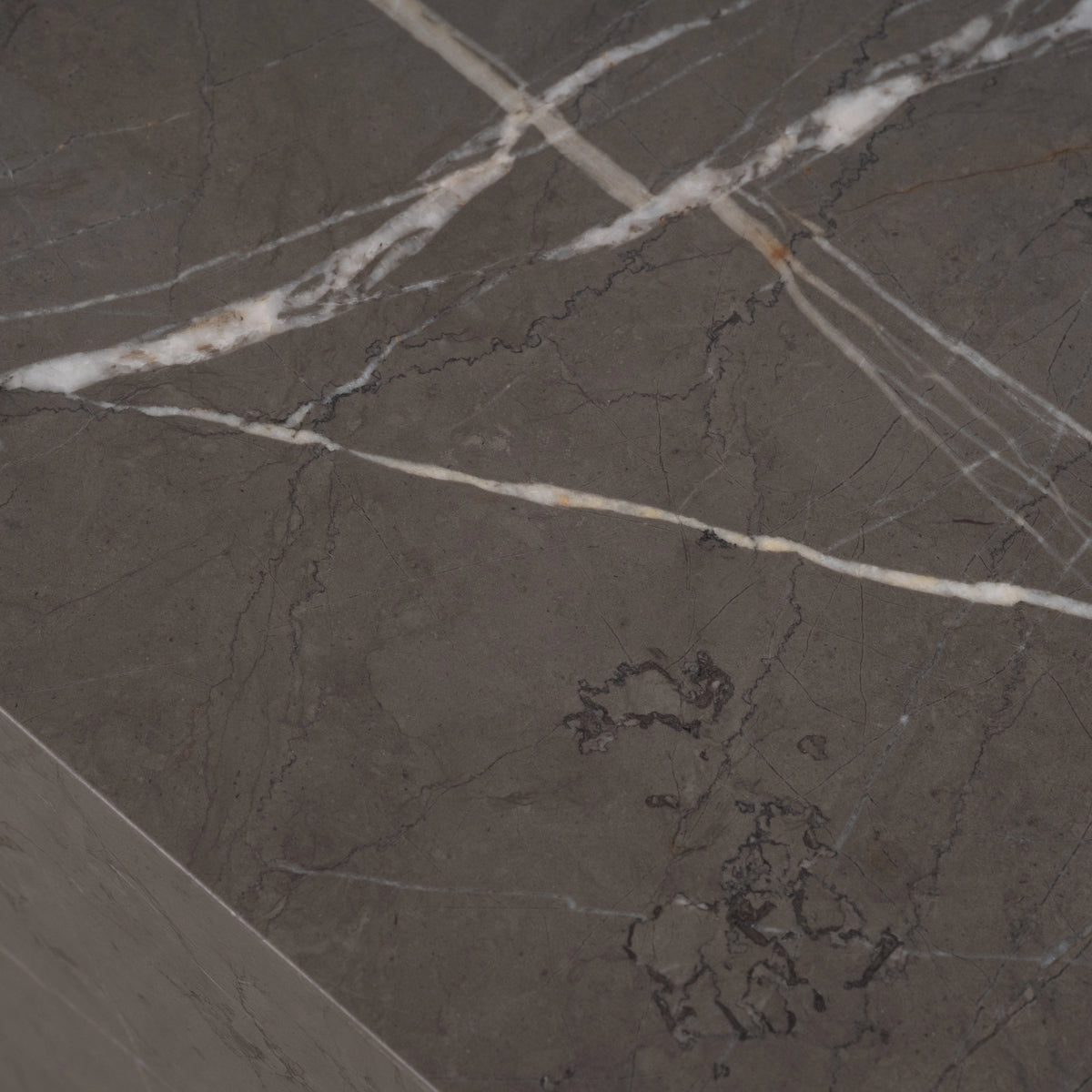 Duvall Coffee Table close-up of the tabletop in warm gray Petra Grey marble, showing bold white veining running toward a crisp squared edge.