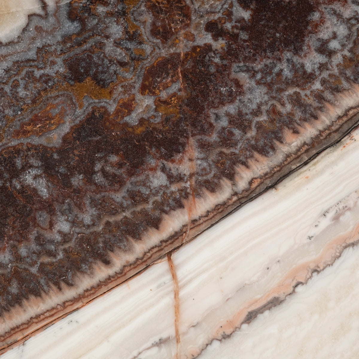 Onyx Side Table top in close-up in cream and brown onyx, showing soft ivory striations, thin peach veins, and a brown band at the upper edge.