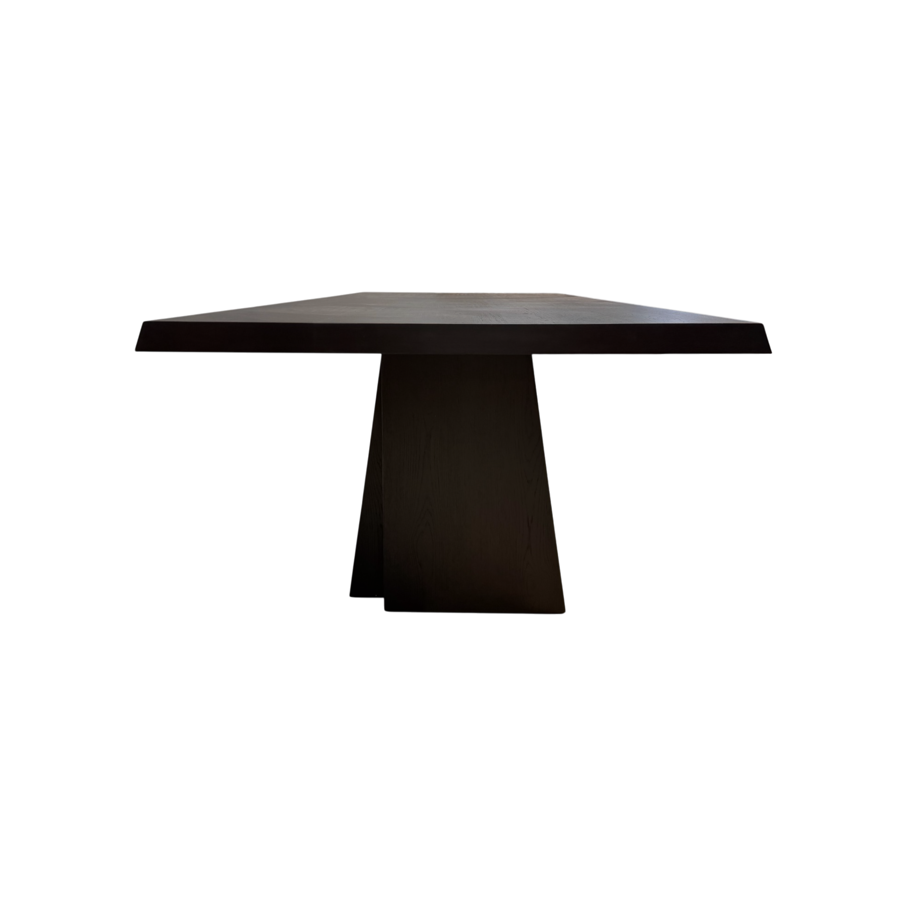 Side view of the Oblique Dining Table highlighting the substantial tabletop and architectural tapered pedestal base.